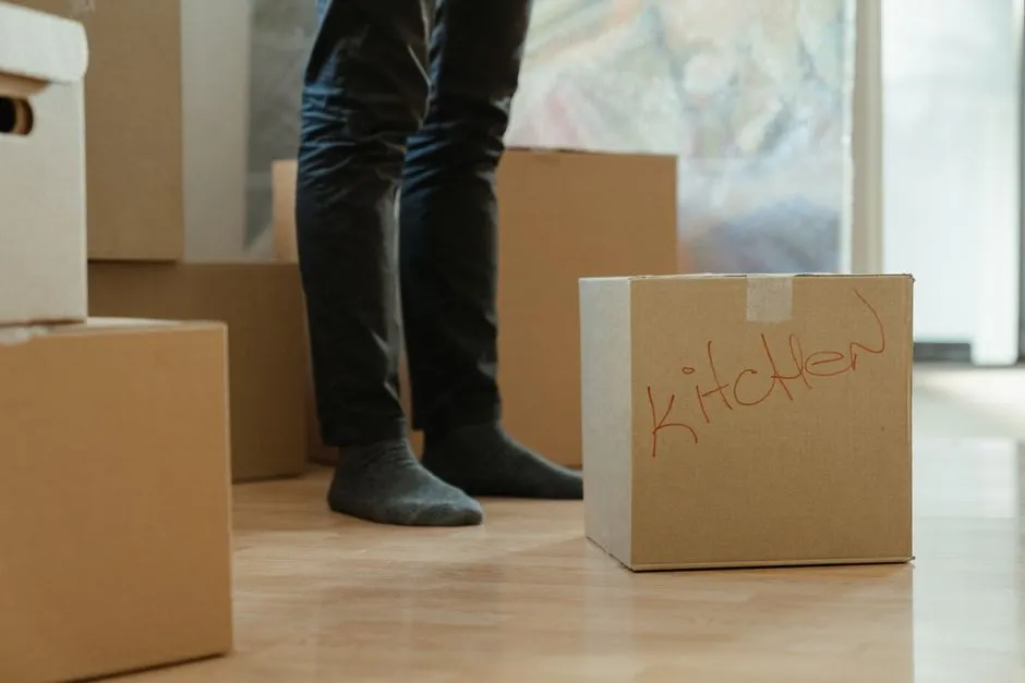 Person standing beside a cardboard moving box during a home move